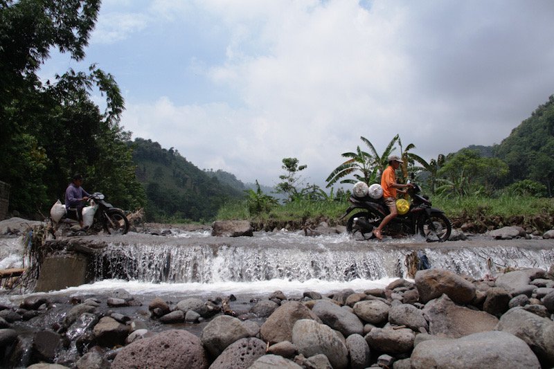 BERBAHAYA : Dua warga nekat menerobos derasnya arus sungai di jembatan limpas penghubung Desa Patemon dengan Desa Wringinanom, Kecamatan Jatibanteng, Kabupaten Situbondo, Minggu 5 Maret 2023. Fotografer: Hozaini