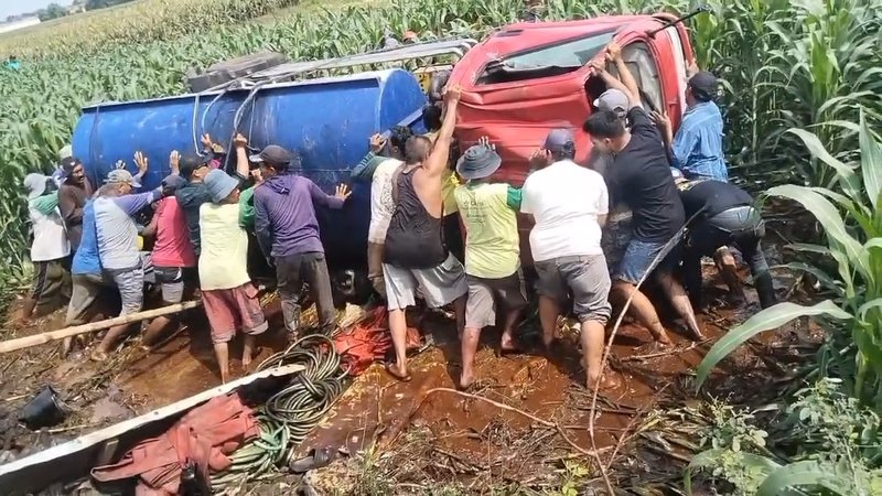 Warga gotong royong membalikkan truk yang terguling di areal persawahan Foto Zulafif